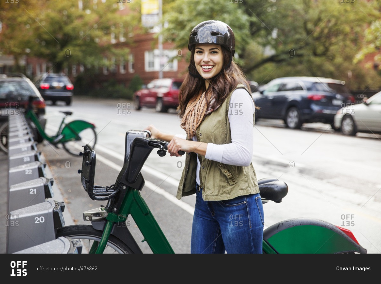 Portrait of smiling woman with bicycle standing at parking lot