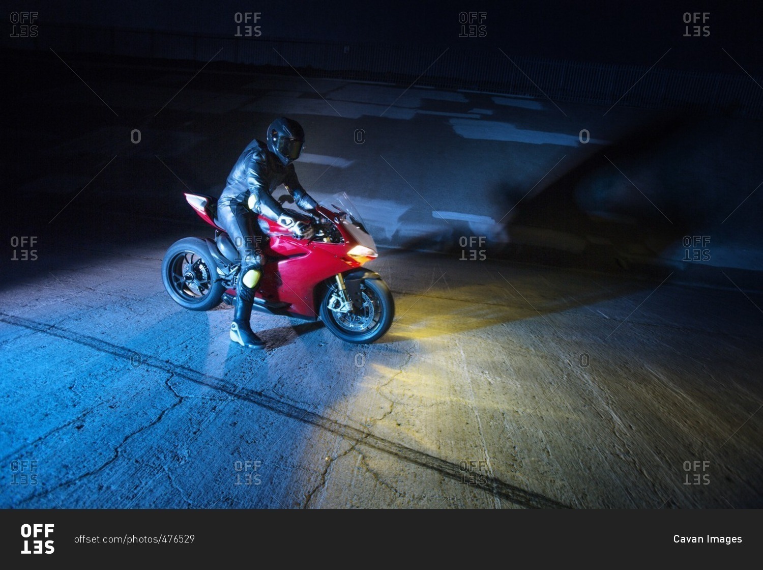 Biker with motorcycle on road at night