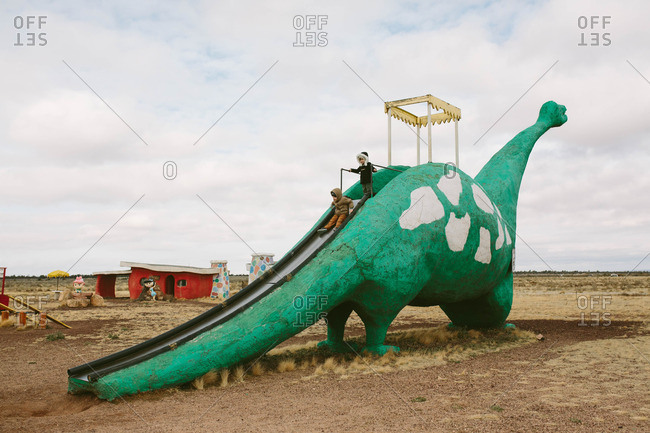 Kids on a dinosaur shaped slide