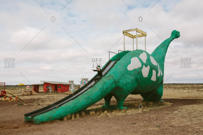 Kid on a dinosaur shaped slide