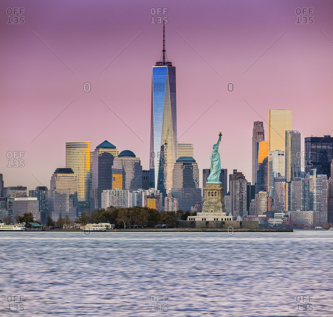 Lower Manhattan, Manhattan, New York City, United States, USA - December 22, 2016:  Statue of Liberty,  One World Trade Center with Freedom Tower across the Hudson River at sunset