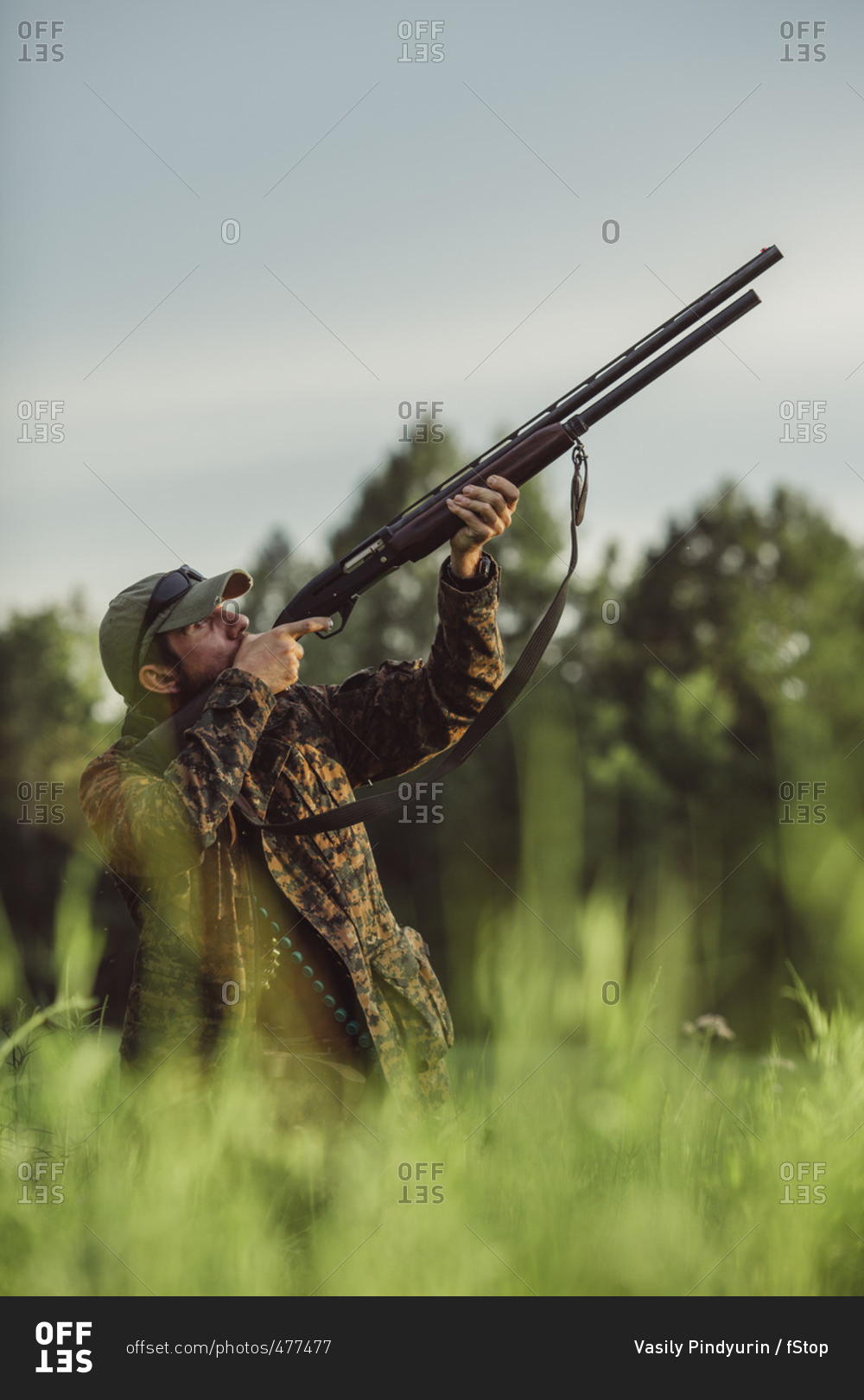 Hunter aiming rifle on field against sky