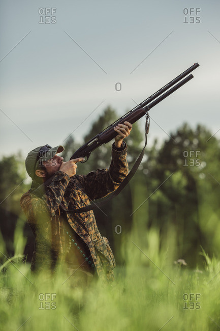 Hunter aiming rifle on field against sky