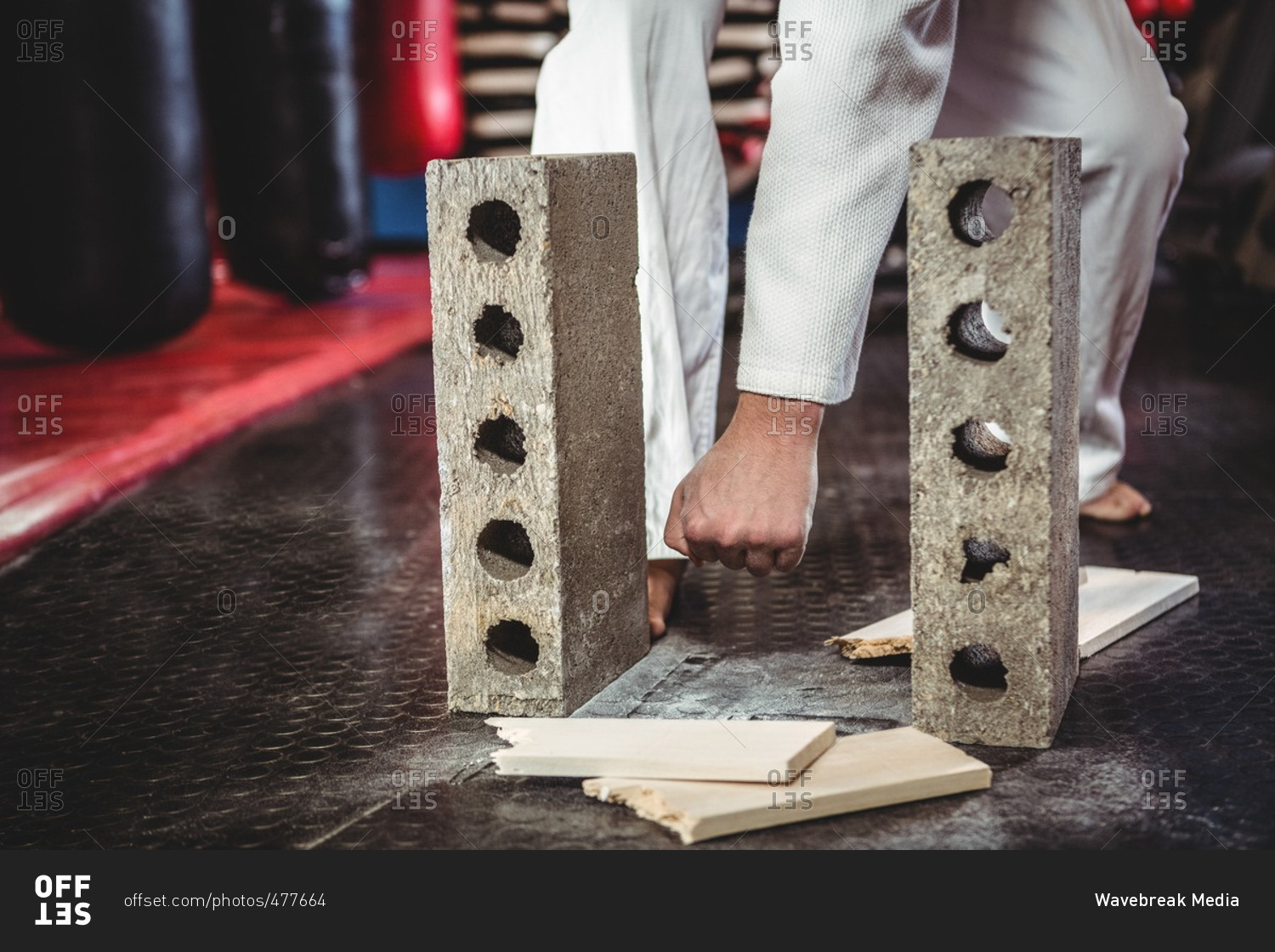 Karate player breaking wooden plank in fitness studio