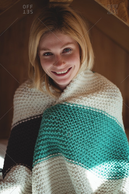 Portrait of beautiful woman wrapped in woolen blanket in bedroom