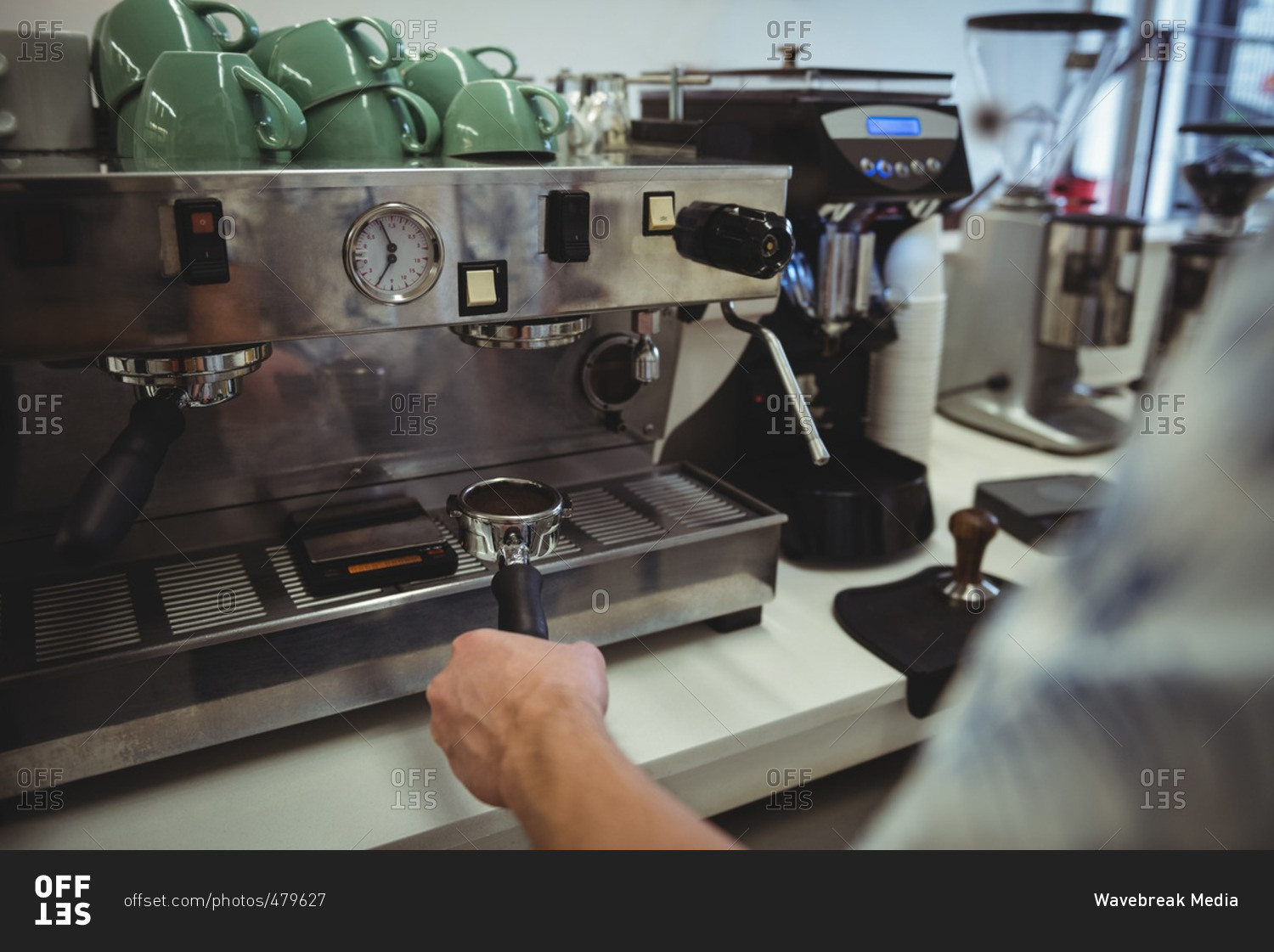 Mid section of man preparing coffee at coffee machine in the coffee shop