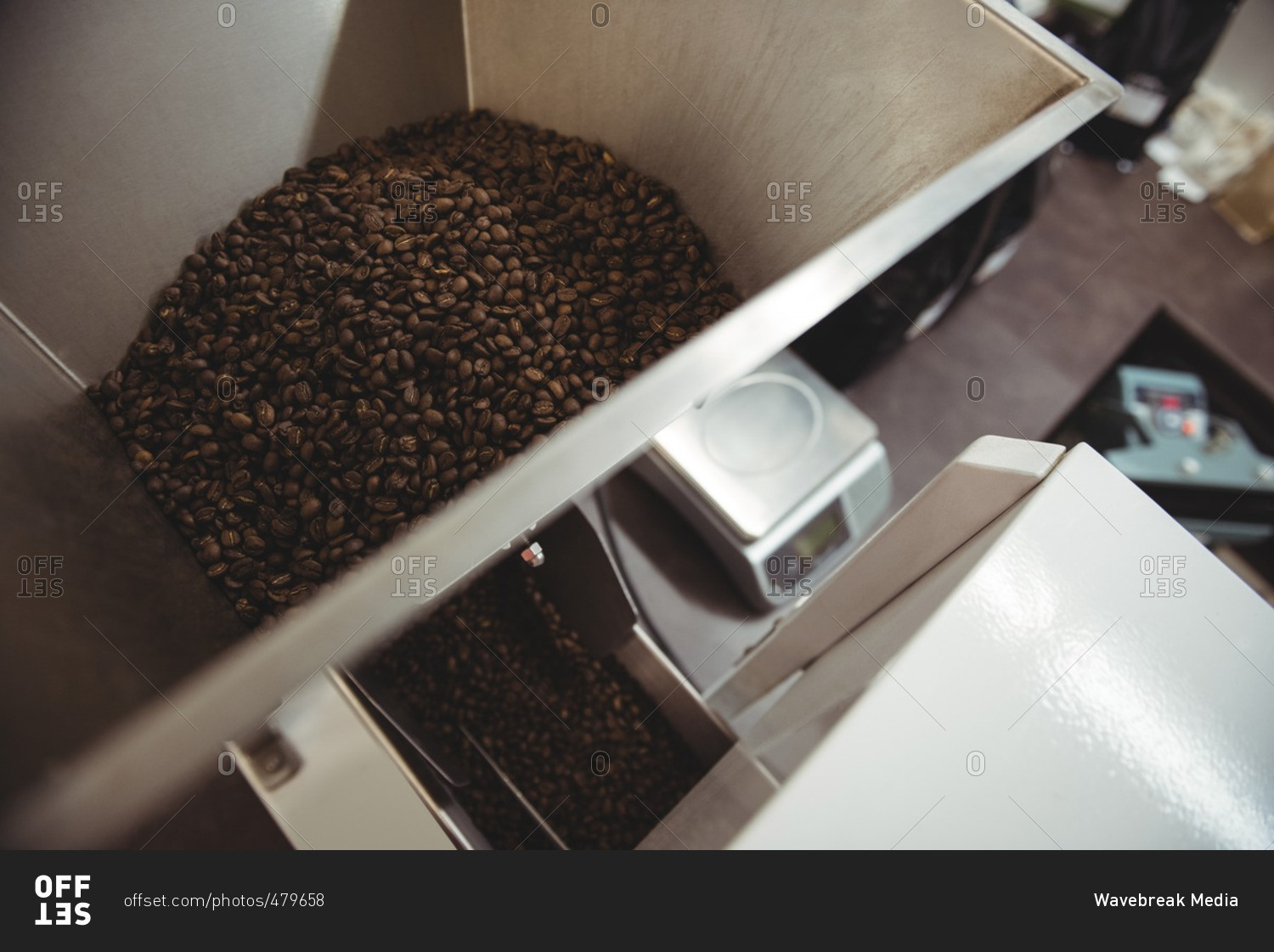 Coffee beans poured inside coffee roasting machine in coffee shop