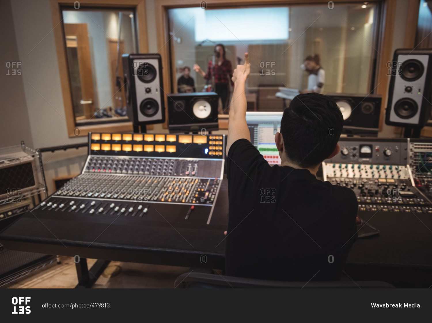 Audio engineer signaling to musicians while recording in studio