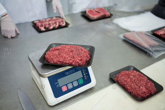 Butchers weighing packages of minced meat at meat factory
