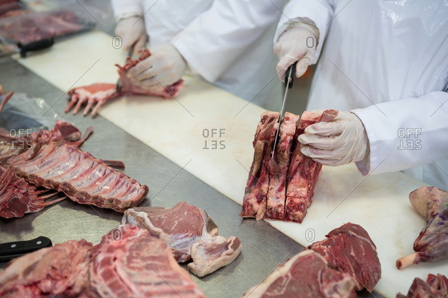 Close-up of butchers cutting meat at meat factory