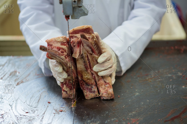 Close-up of butcher cutting meat with meat cutting machine