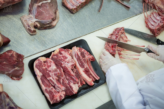 Close-up of butcher cutting meat at meat factory