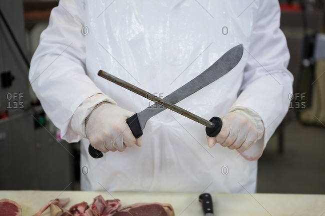 Butcher sharpening his knife at meat factory