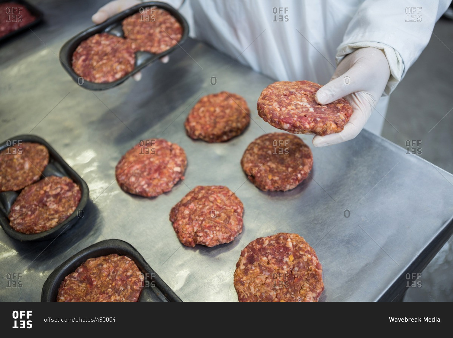 Closeup of butcher packaging hamburger patty at meat factory stock