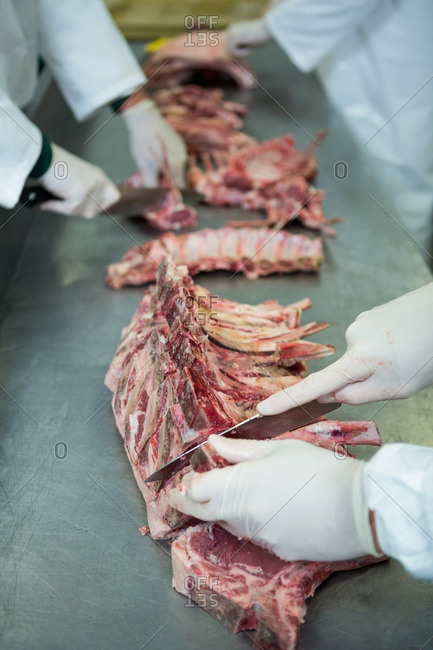 Close-up of butchers cutting meat in meat factory