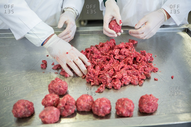 Mid-section of butchers preparing meat balls in meat factory