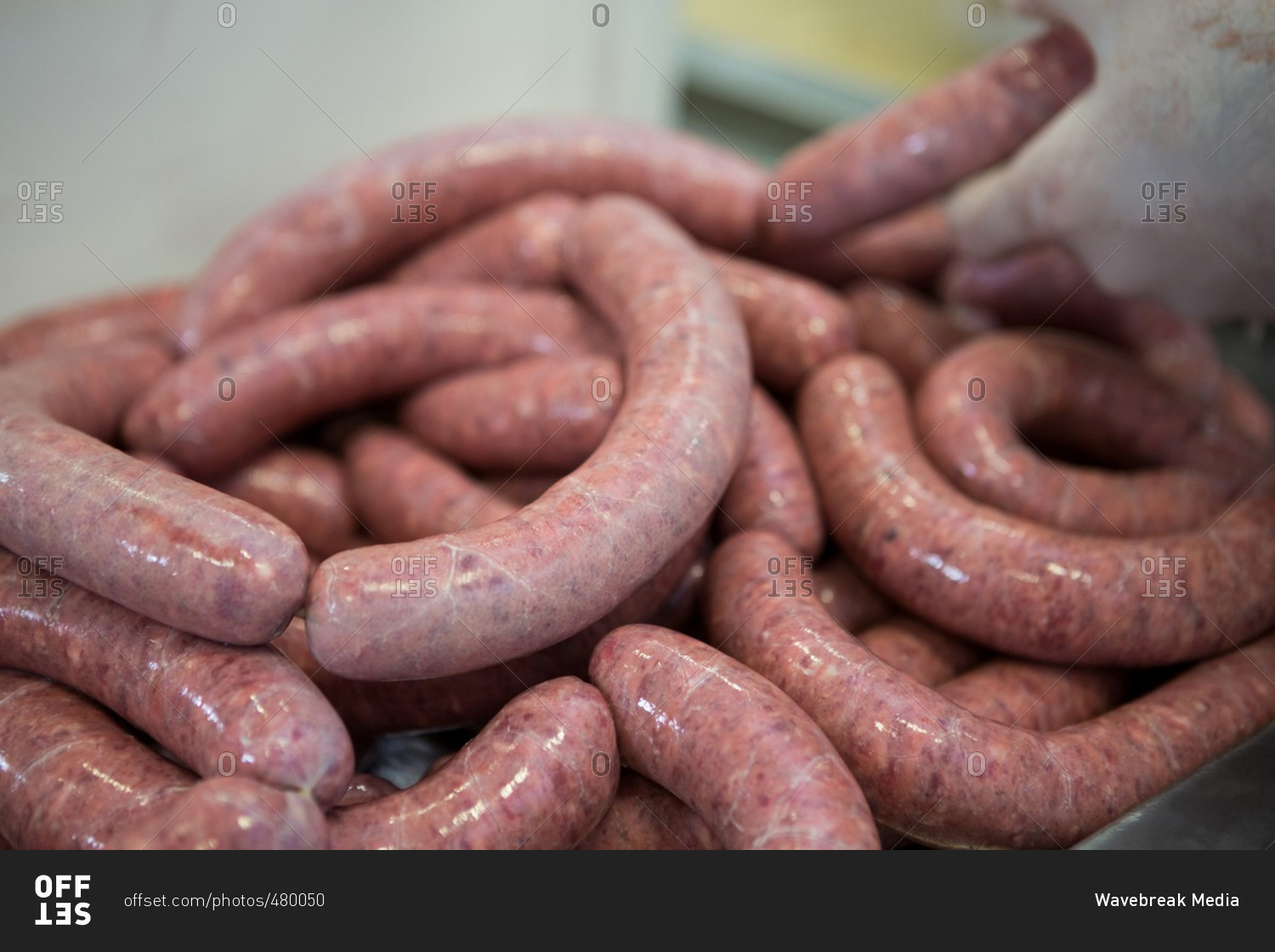 Close-up of butcher processing sausages in meat factory