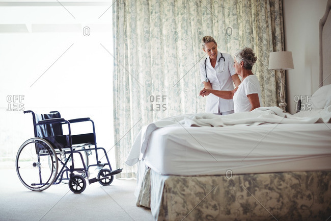 Female doctor consulting senior patient in bedroom