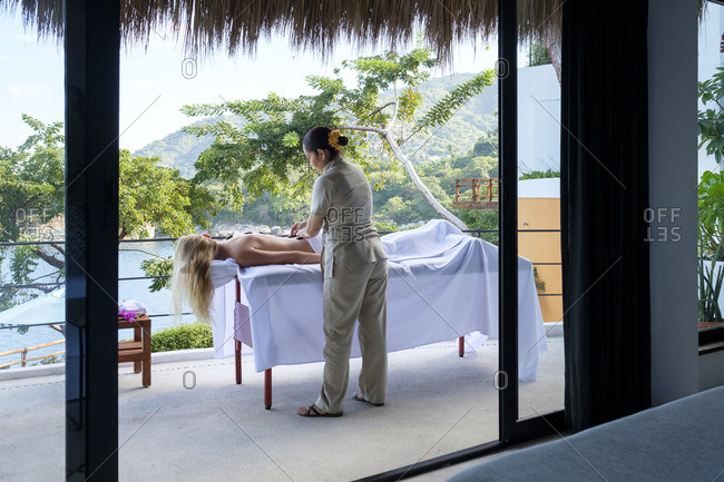 Young woman receiving a massage on the balcony of her suite in a luxury vacation retreat