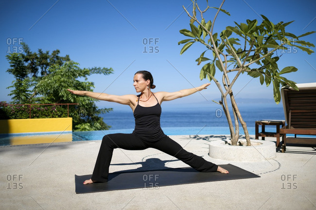 Woman practicing yoga at ocean front resort