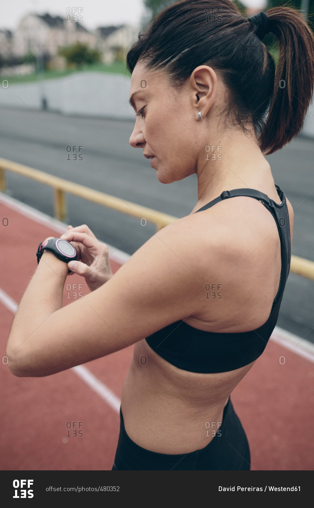 Athlete on tartan track looking on smart watch