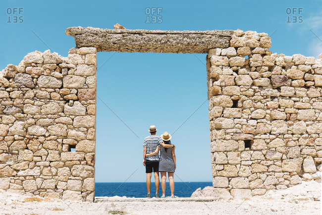 Firopotamos Beach- Couple standing in door in stone wall- looking at distance