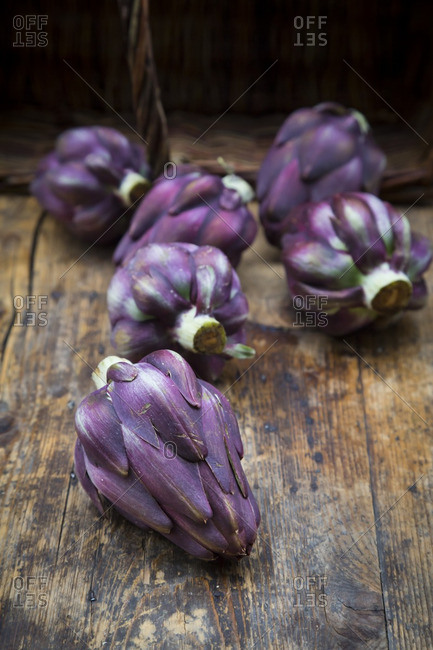 Purple organic artichokes on dark wood