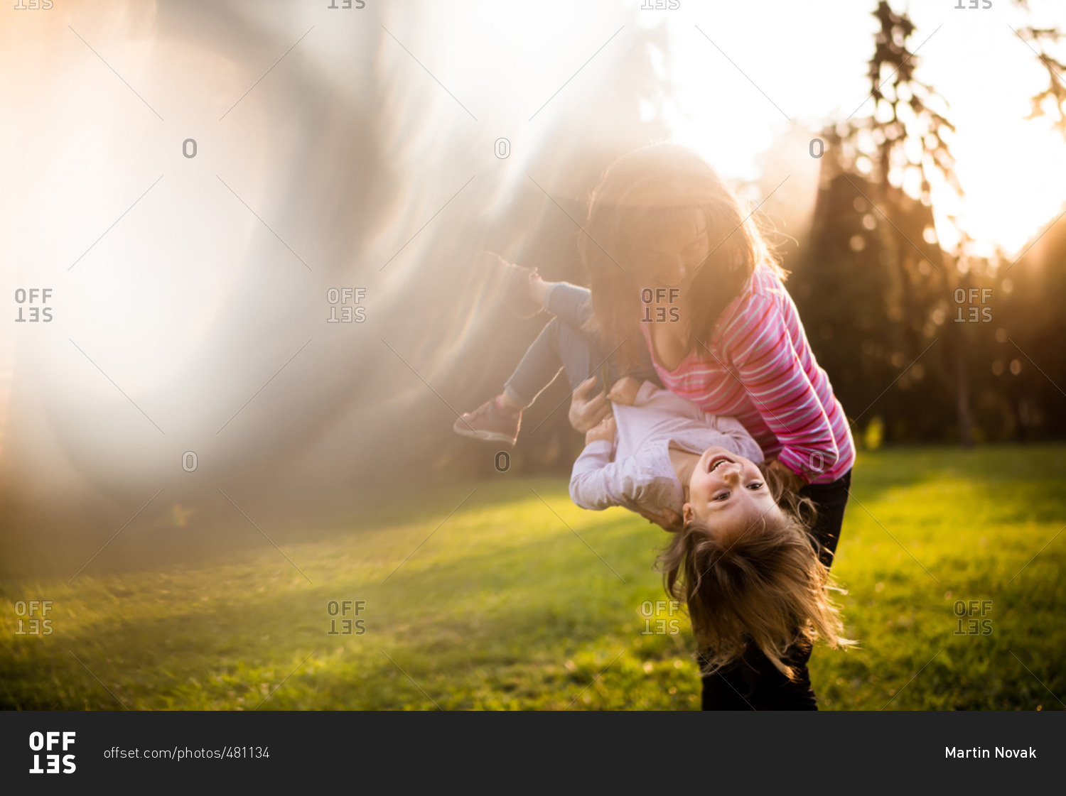 Mother playing with daughter and holding her upside down