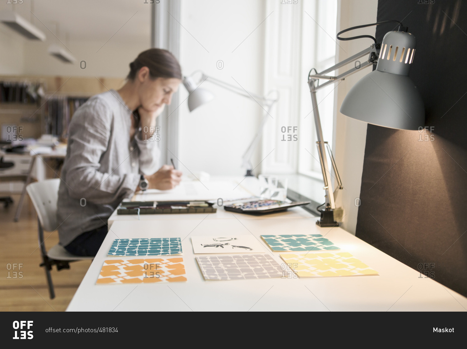 Woman painting on canvas by illuminated desk lamp at creative office