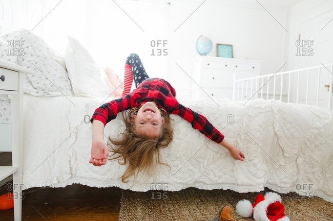 Girl Upside Down On Bed By Santa Hat Stock Photo Offset