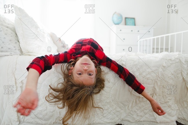 Girl in flannel upside down on bed