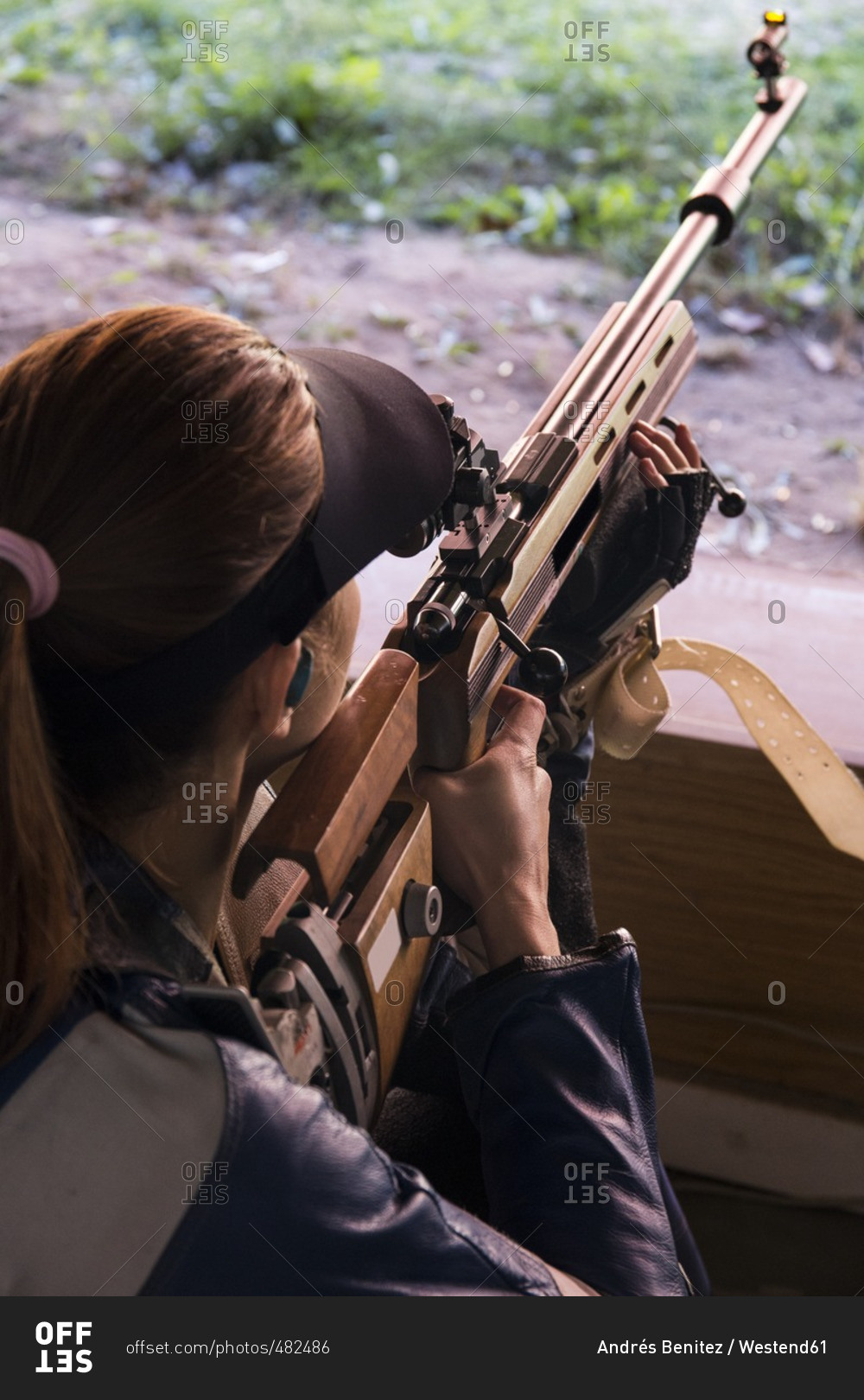 Woman with a sporting rifle aiming in a shooting range