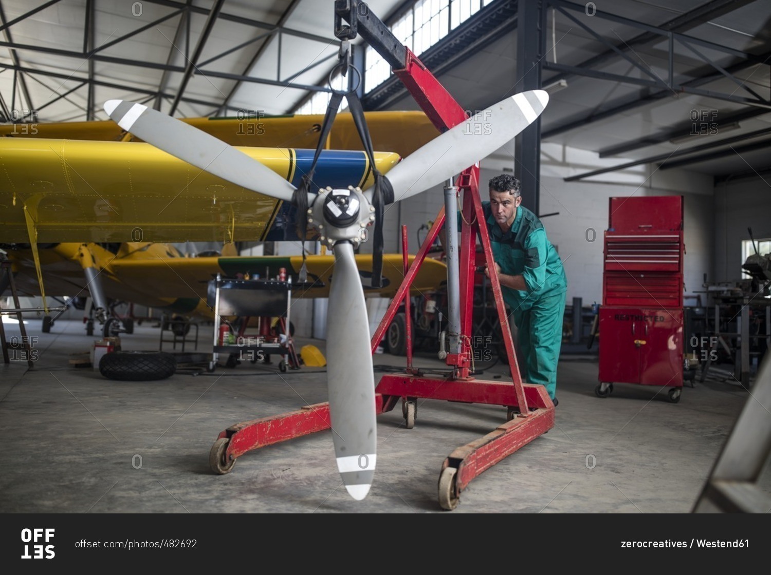 Mechanic in hangar pushing propellor of light aircraft