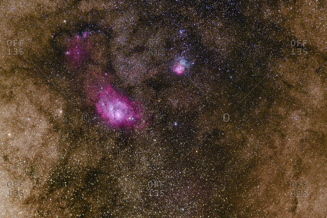 The Lagoon Nebula and the smaller Trifid Nebula along with dark dust clouds in the Milky Way band