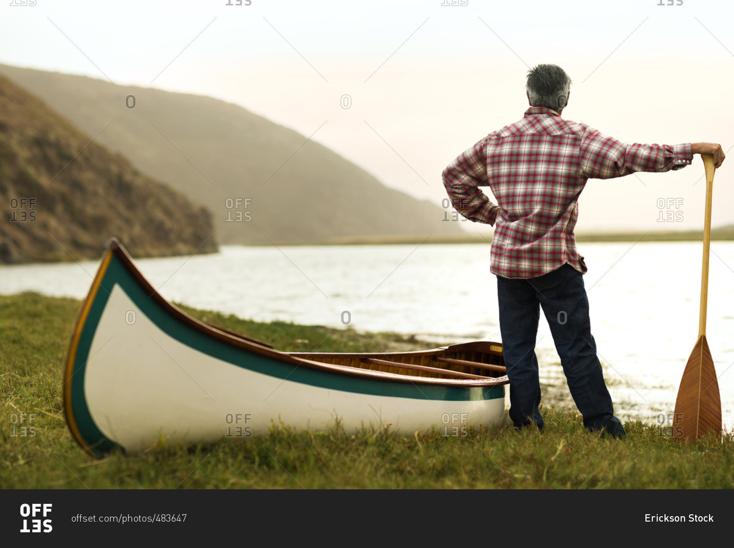Mature man standing at the water\'s edge with his canoe