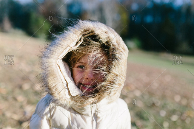 Portrait of a little girl with windblown hair in hooded coat