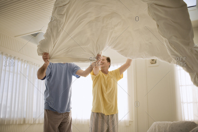 Two men making the bed together.