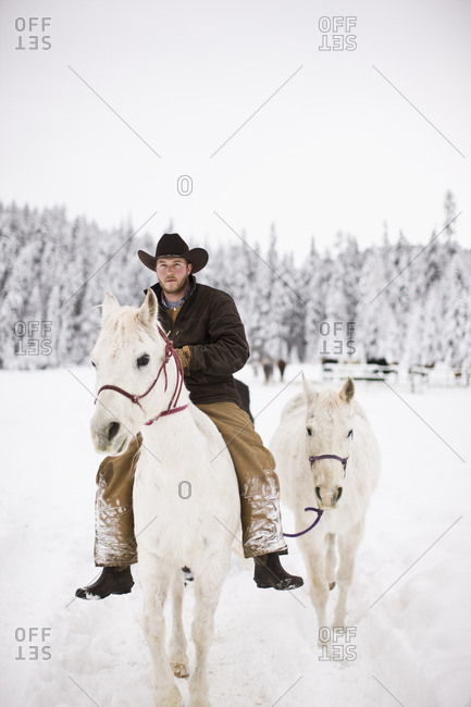 Cowboy on horseback leading another horse.