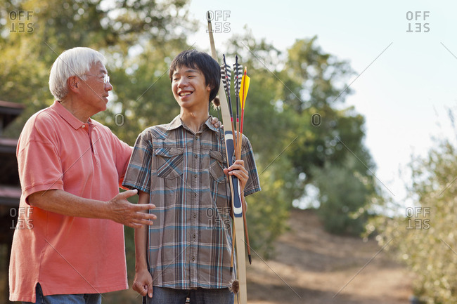 Senior man and his teenage son on an archery expedition.