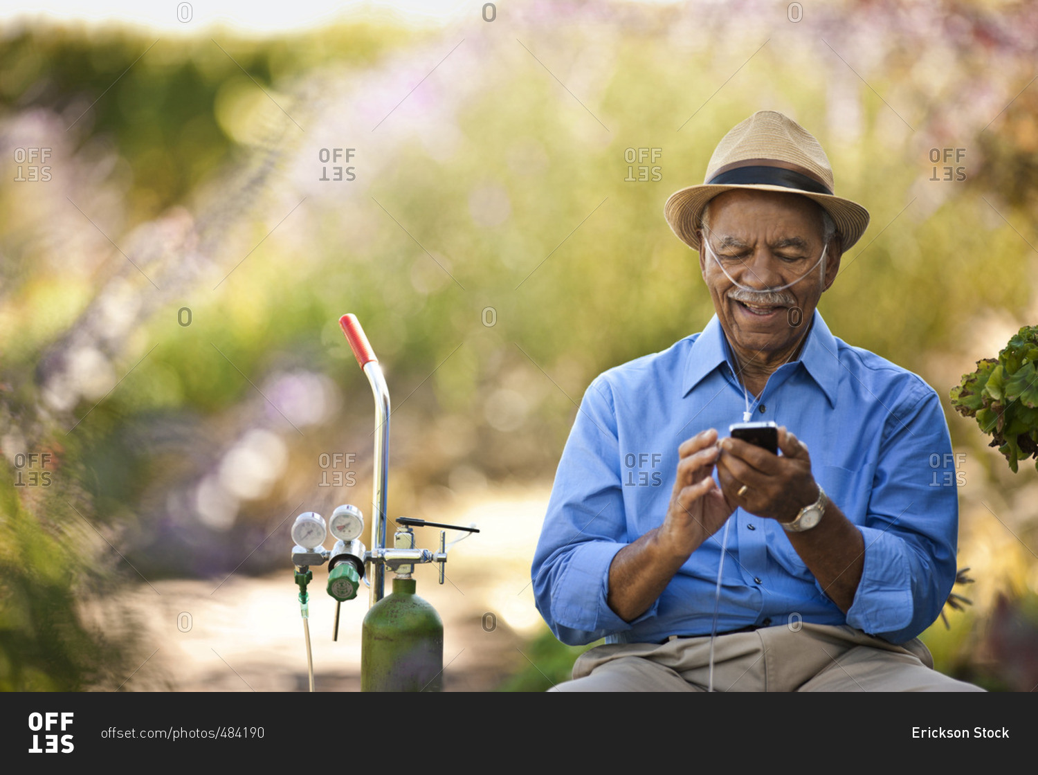 Senior man on breathing apparatus using a cellphone.