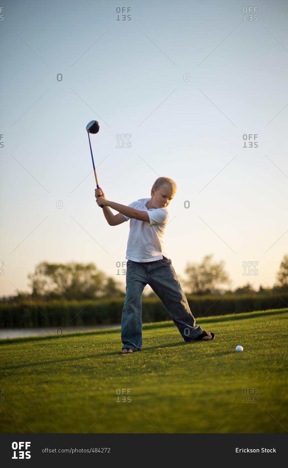 Young boy swinging a golf club.