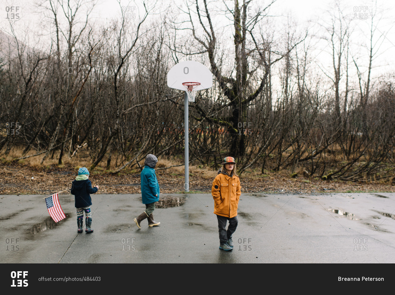 Children playing on basketball court in rainy weather