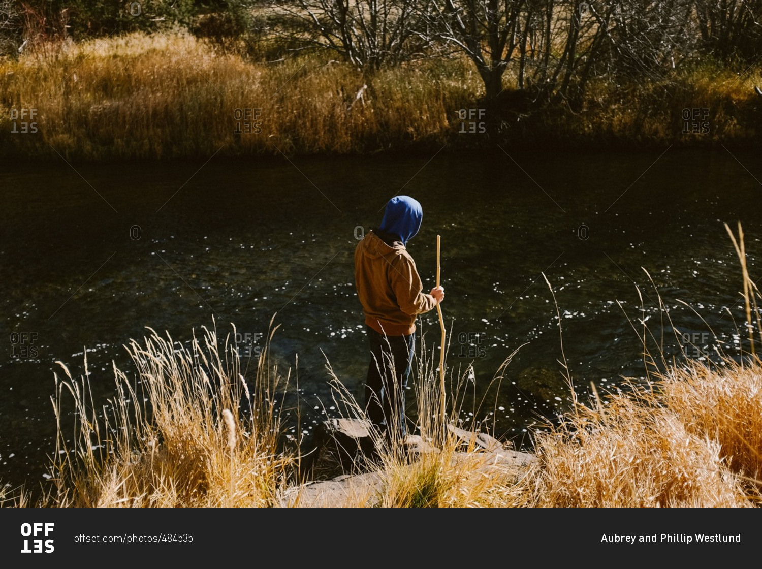 Person by shore of rural river in fall