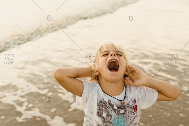 Little boy standing by the ocean screaming