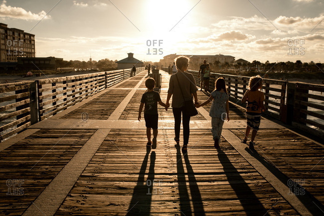 Mother walking with children on a boardwalk at sunset
