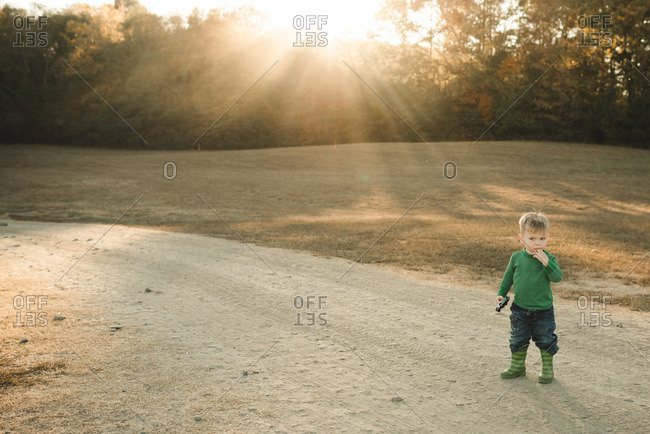 Toddler boy standing on a dirt path at sunset