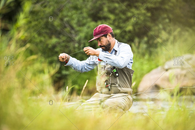 A Fly Fisherman Prepares His Gear While Sitting Next To The Yampa River, Colorado.