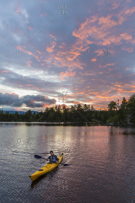 A Man Paddles His Kayak On Long Pond In Maine's North Woods Near Greenville, Maine