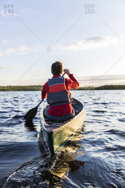 A Man Paddles His Canoe On Long Pond In Maine's North Woods Near Greenville, Maine