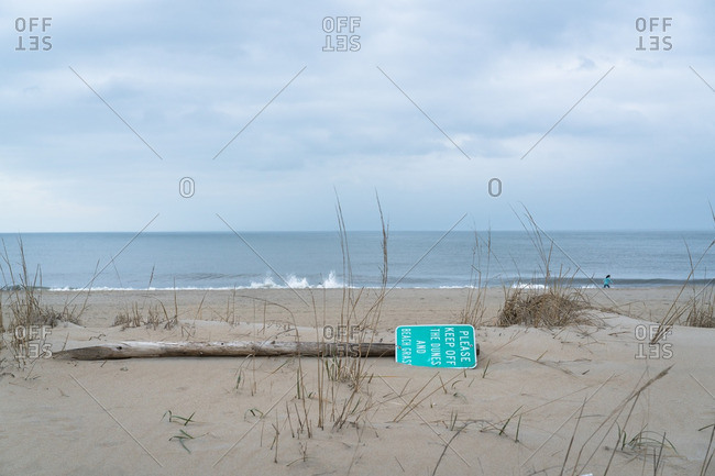 Fallen sign warning to keep off dunes on beach